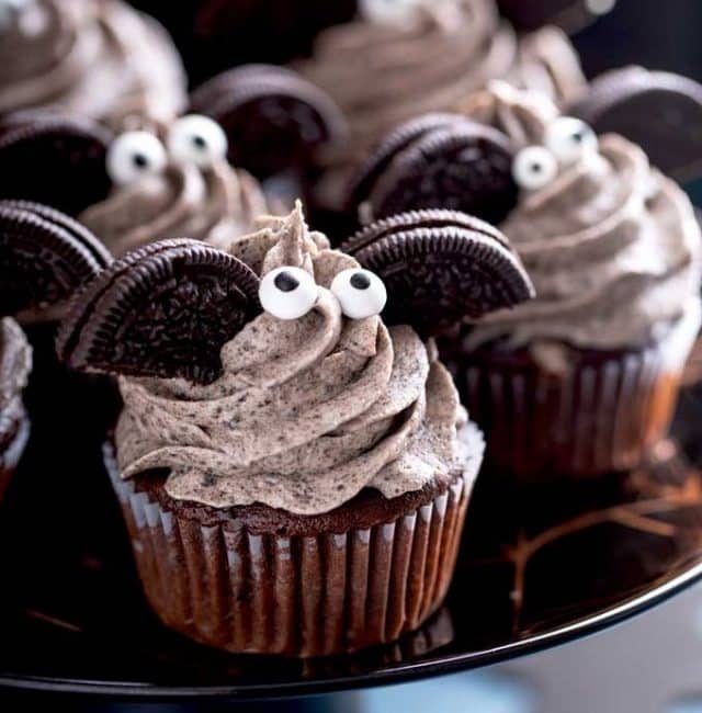 Cupcakes with cookies and cream frosting, half Oreos as wings and little eyes, on a cake platter