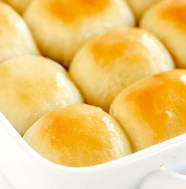 Golden brown soft dinner rolls in a baking dish.