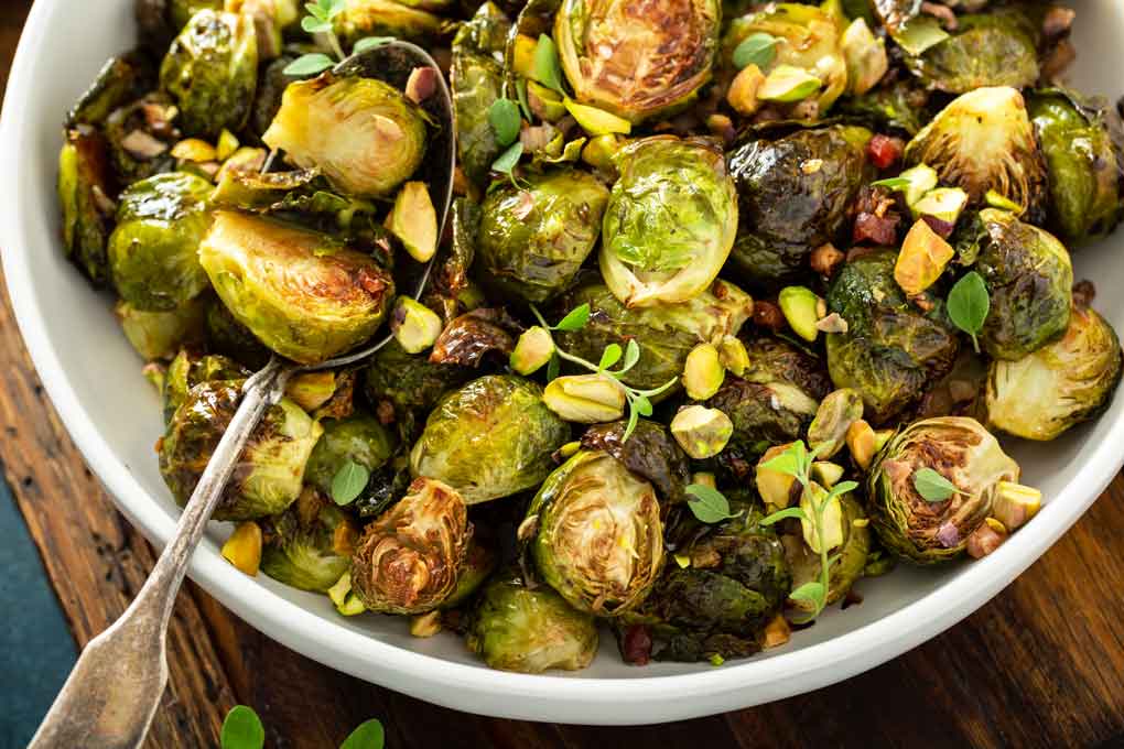 Spoon scooping oven baked caramelized Brussels Sprouts with bacon.