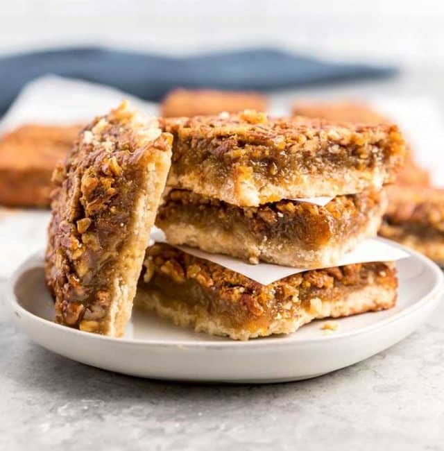 Pecan pie squares stack on a white plate