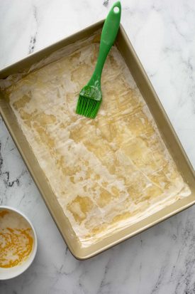 Brushing a layer of phyllo dough with melted butter