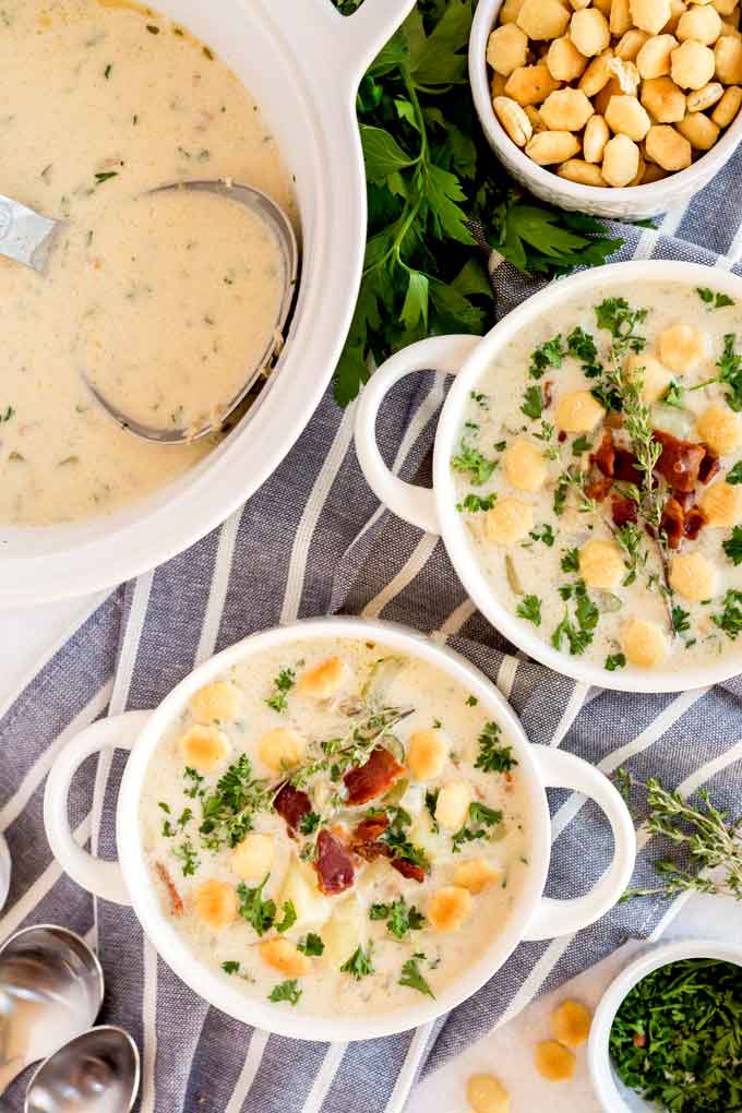White bowls filled with creamy clam chowder and topped with crispy bacon