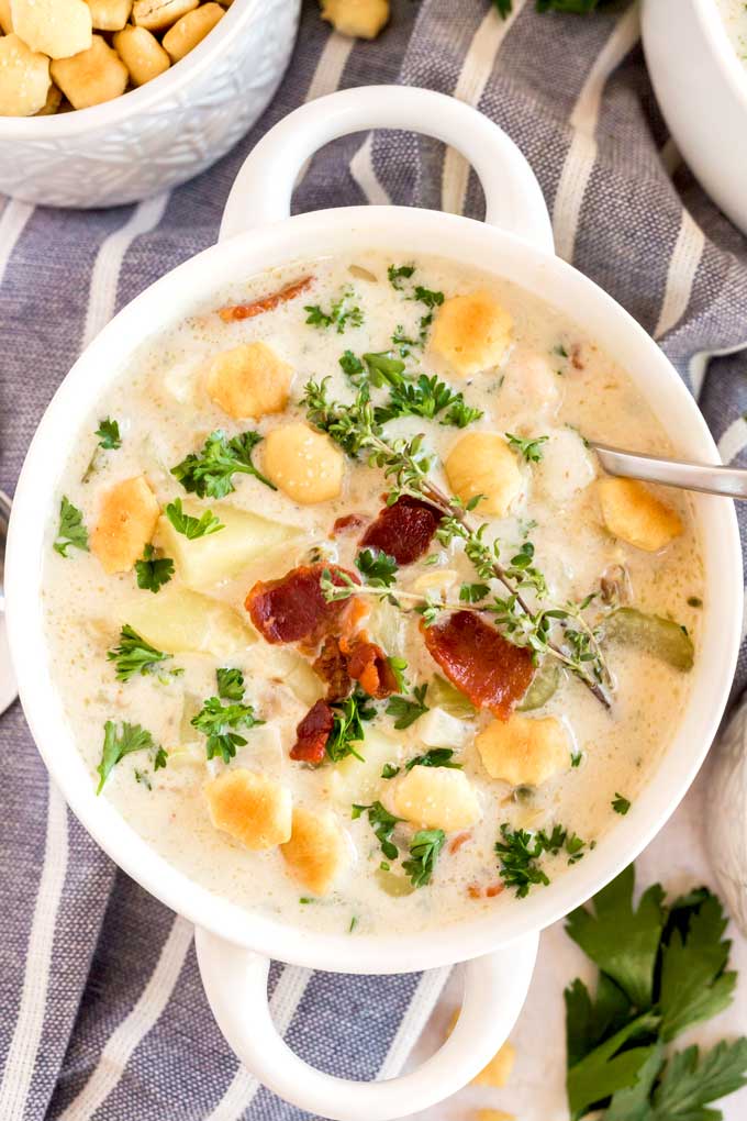Clam chowder with bacon on top in a white bowl.