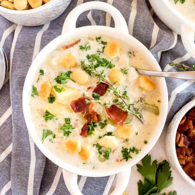 A bowl of creamy clam chowder topped with crispy baconm