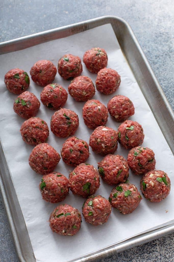 meatballs lined up on a sheet pan