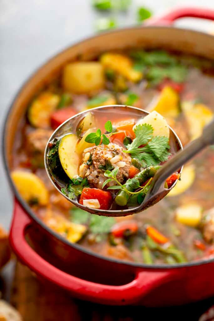 A big spoon scooping Albondigas Soup from the pot.