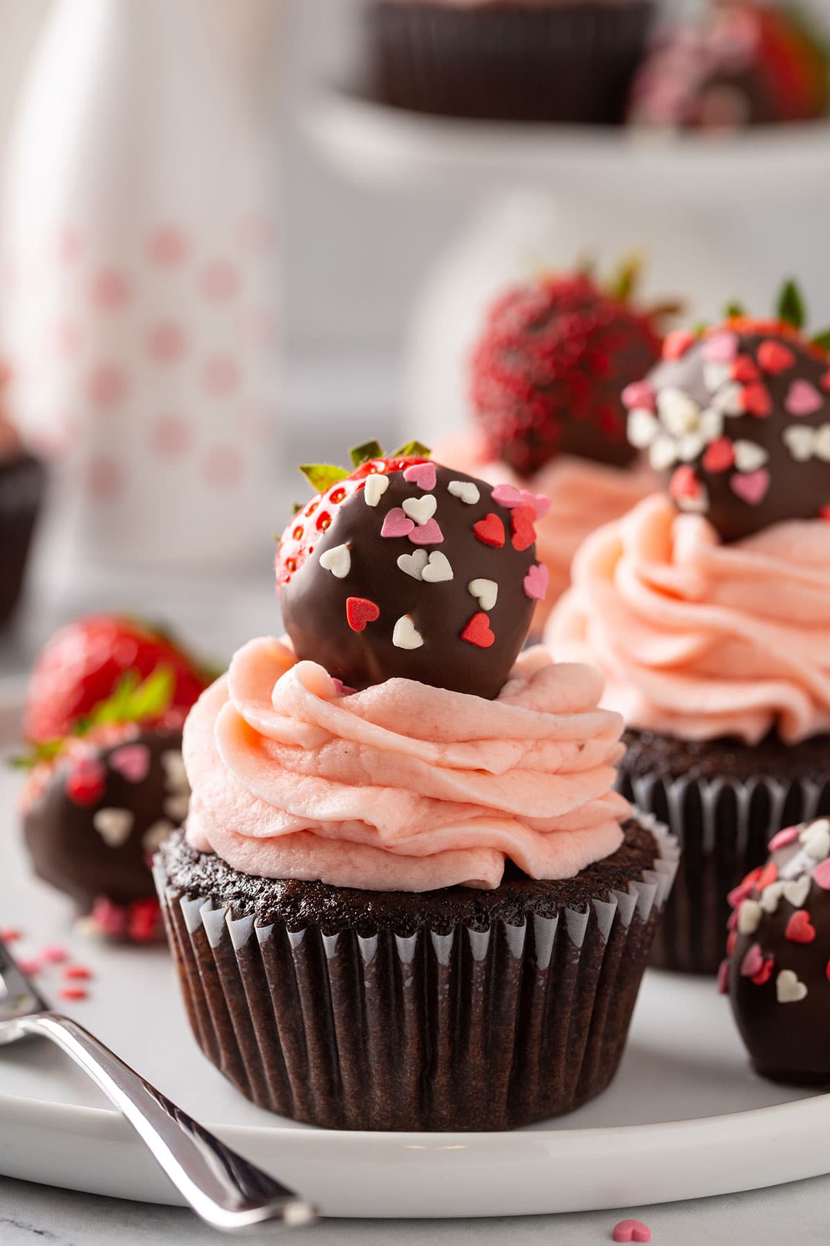 Close up to a cupcake topped with a chocolate covered strawberry