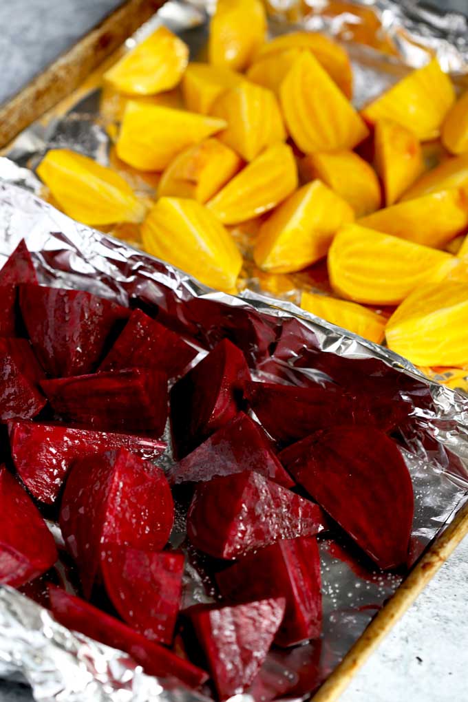 Golden and Red Beets cut into quarters drizzled with oil and seasoned on a sheet pan