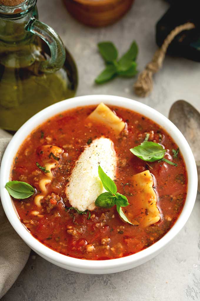 A bowl of lasagna soup topped with cheese.