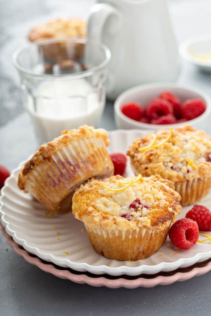 Three raspberry muffins with streusel on a white plate.