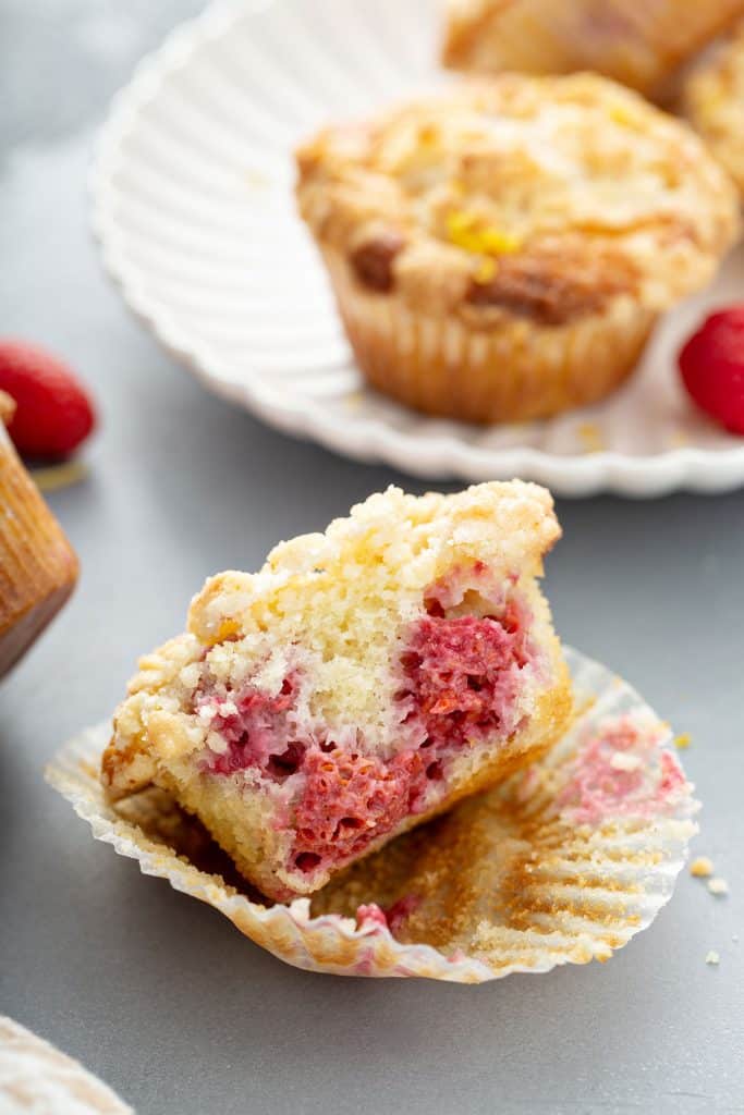 Half of a muffin showing the tender crumb and raspberries