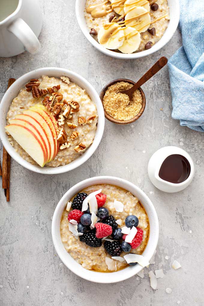 Three bowls of instant pot steel cut oatmeal topped with assorted fruit.