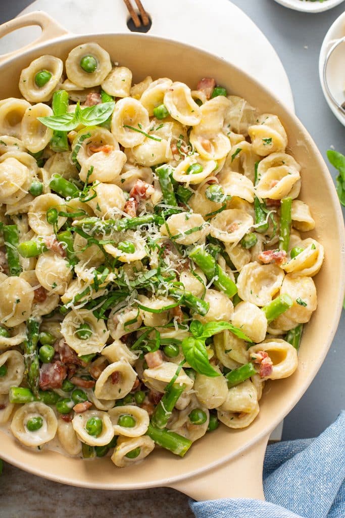 top view of a skillet with pasta with asparagus and bacon in a creamy lemon sauce