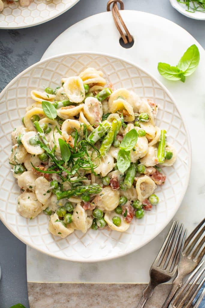 top view of a plate of creamy lemon pasta with asparagus, peas and pancetta.