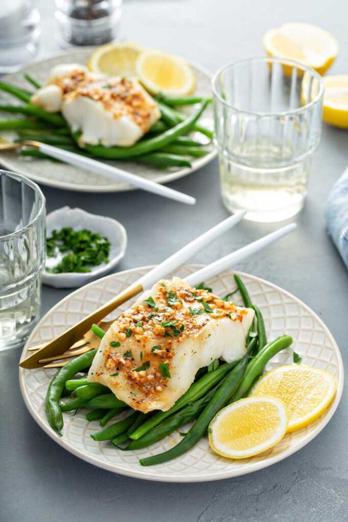 Plates served with easy baked fish fillets with cajun butter and green beans