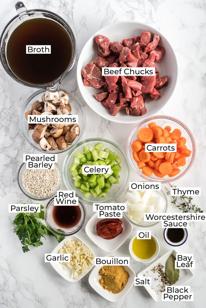 Ingredients to make Beef and Barley Soup over a marble surface 