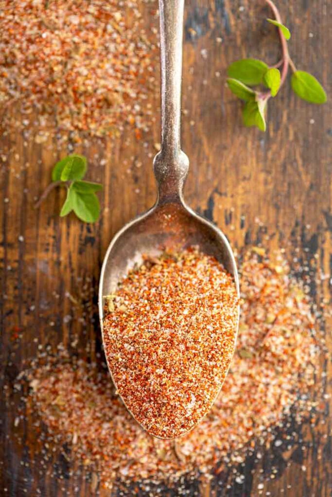 A spoonful of Cajun seasoning on a wooden table