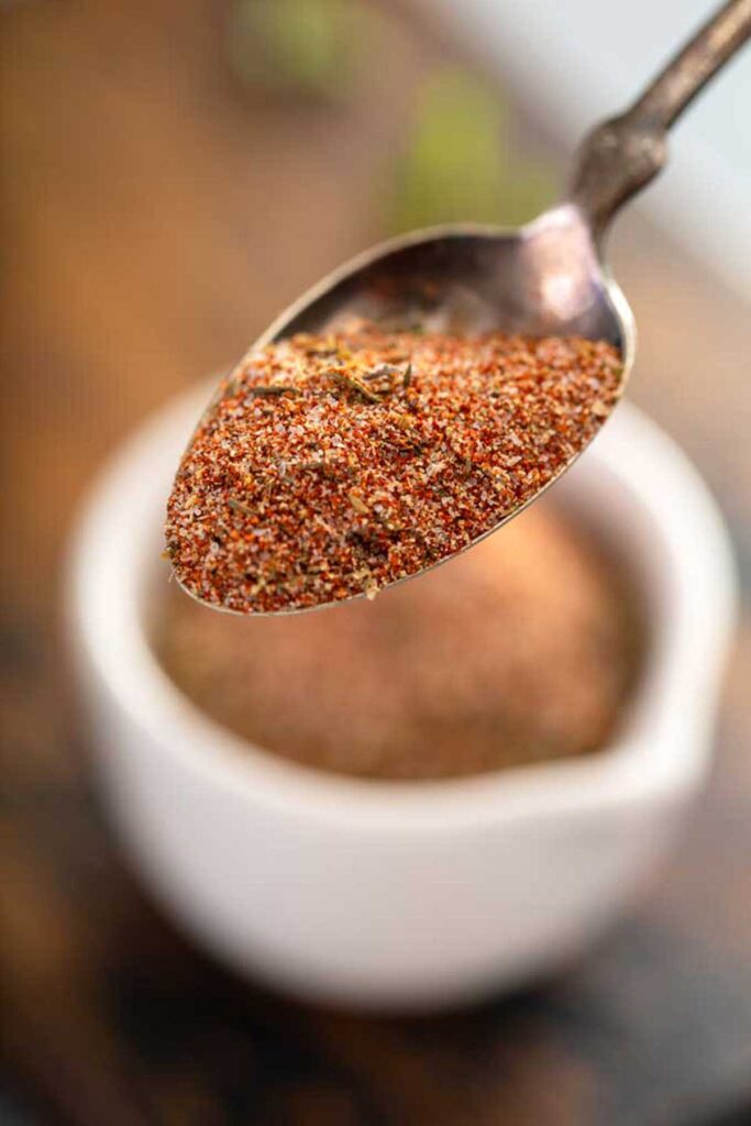 Spoonful of seasoning mix lifted from a white bowl