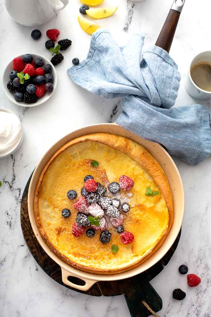 Top view of a dutch baby pancake topped with berries and powdered sugar