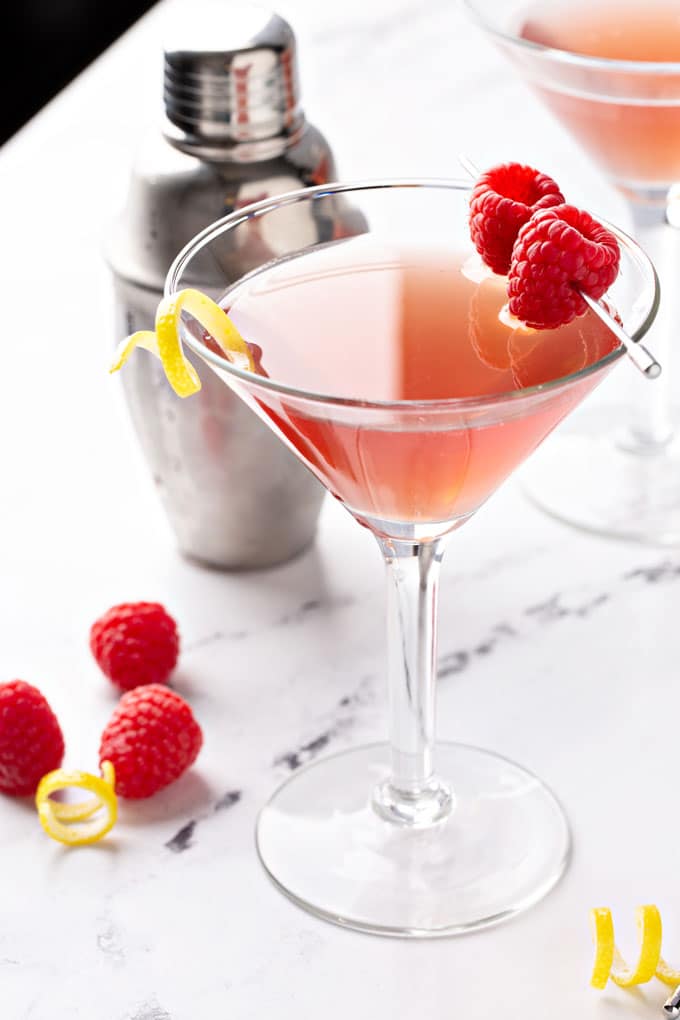 A martini glass with pinkish French martini with fresh raspberries