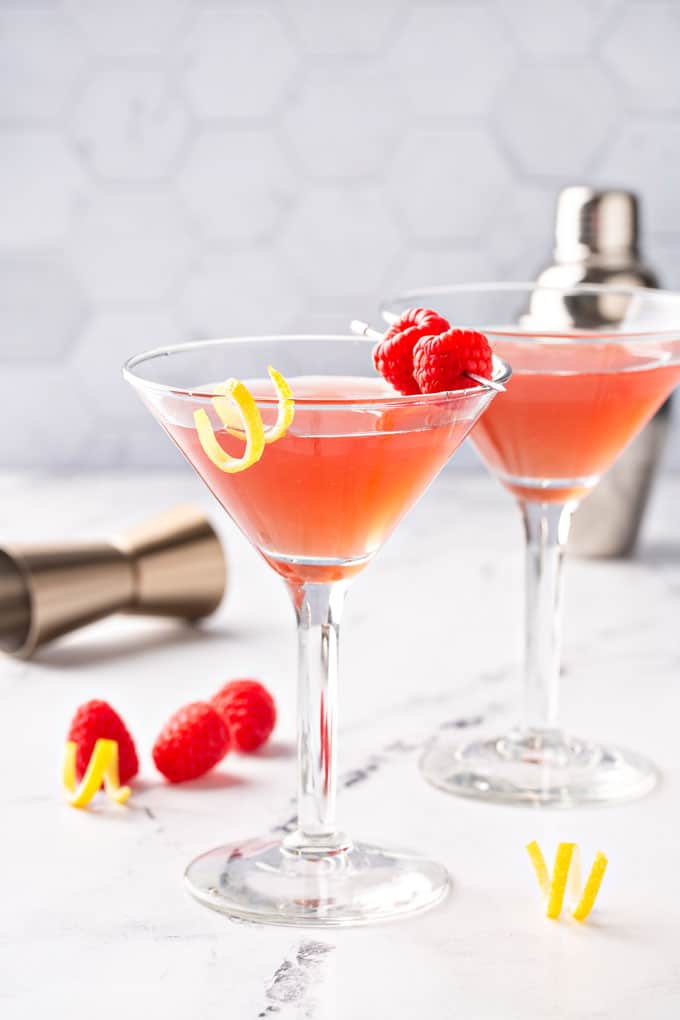 A couple of martini glasses with a lemon twist and raspberries.