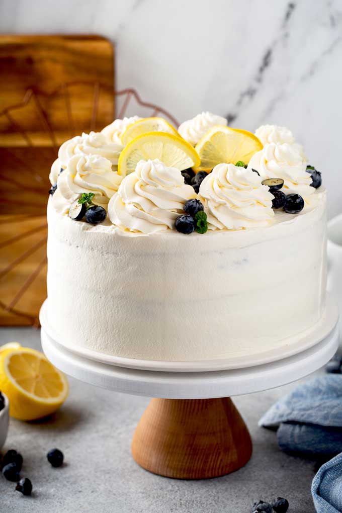 A cake covered in whipped mascarpone frosting on a cake plate.