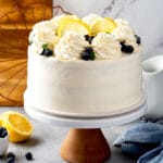 a whole 3 layer cake covered with mascarpone frosting and garnished with blueberries and lemon slices