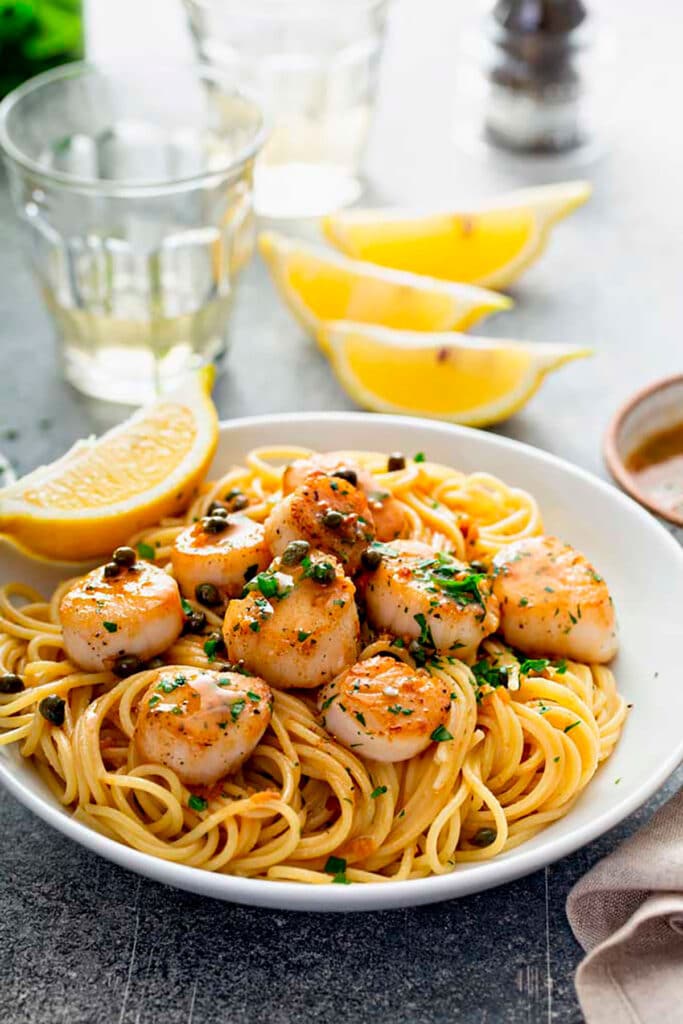 A white bowl of pasta with Seared Scallops with Lemon Garlic Butter Sauce