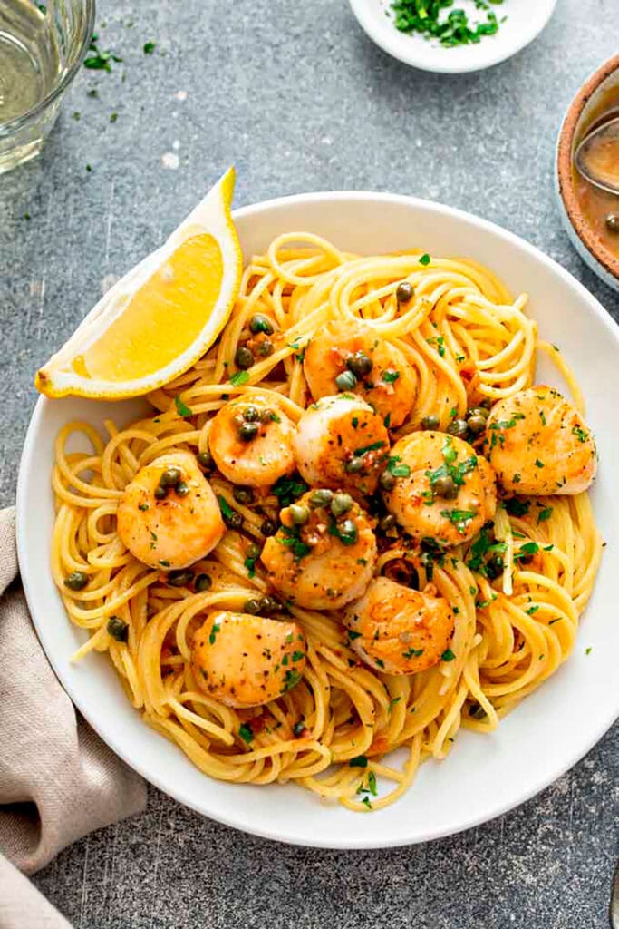 Top view of Seared Scallops wih pasta on a white plate 