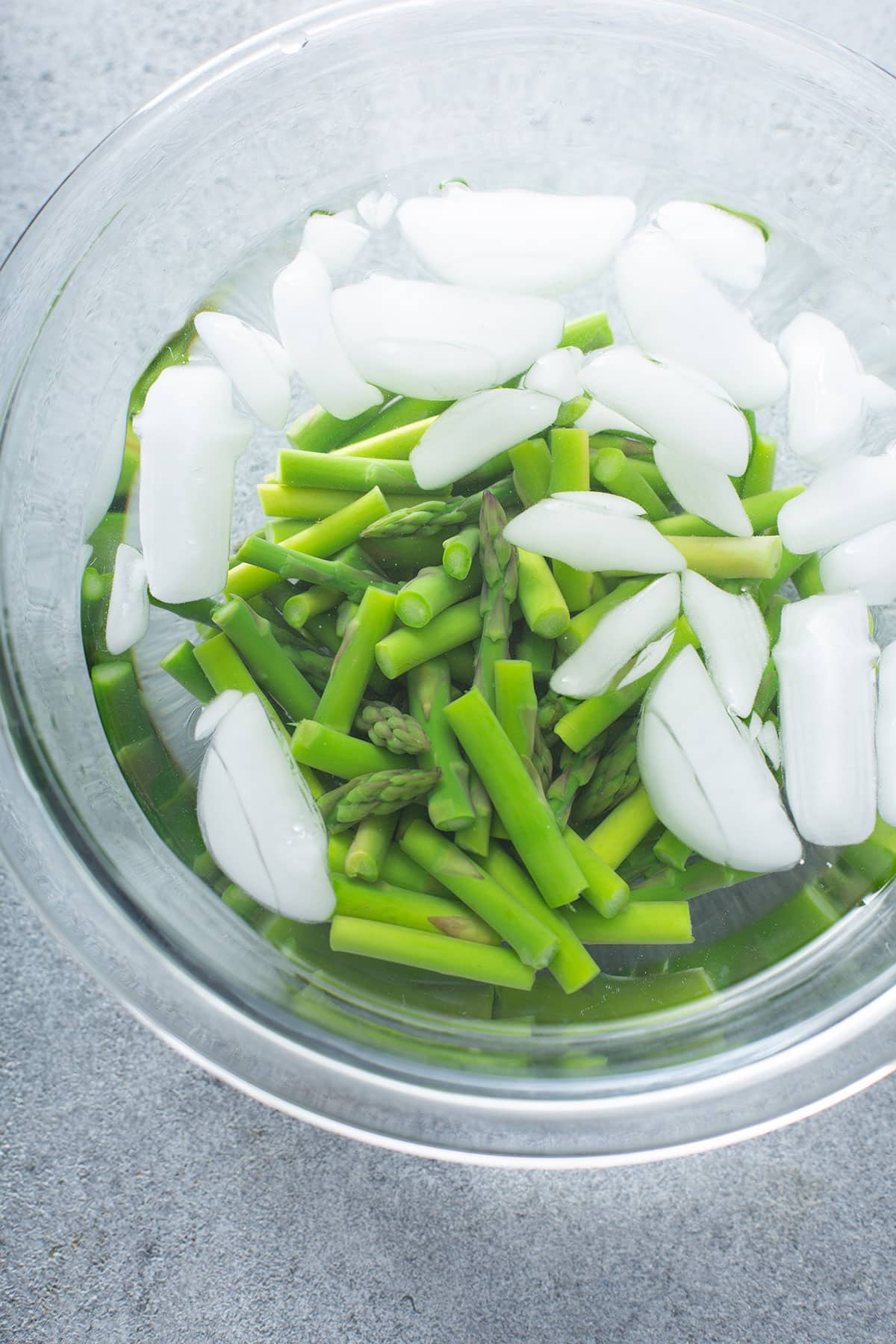Shocking asparagus in iced water after blanching.
