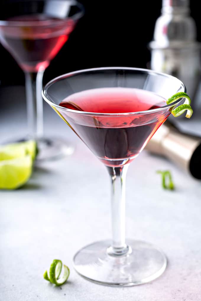 A martini glass filled with cosmopolitan cocktail martini on a light surface