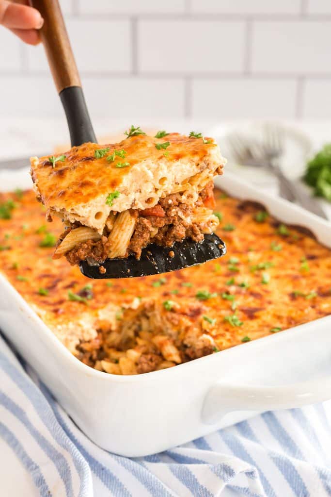A slice of pastitsio getting served from a baking dish