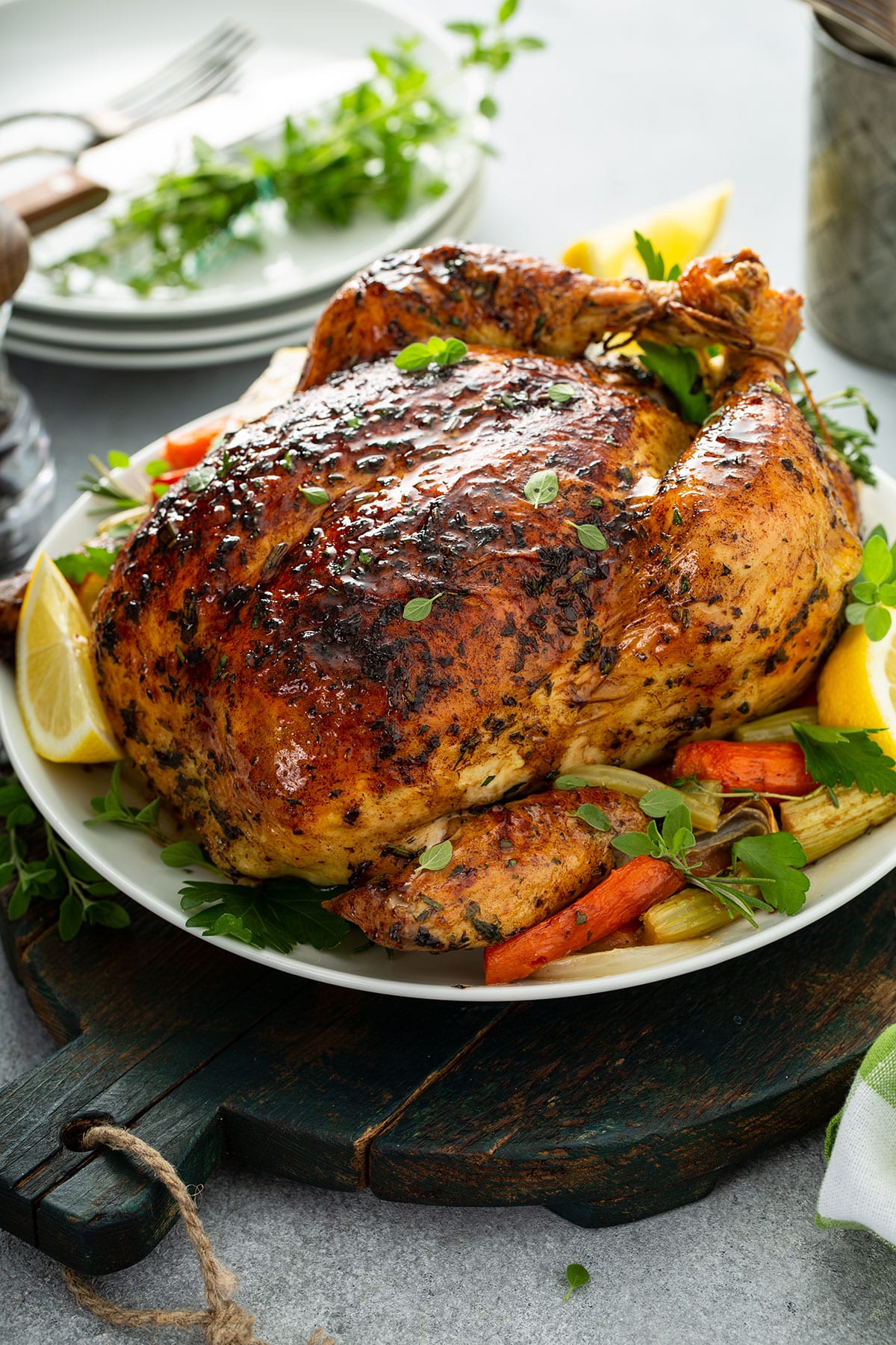 a whole roasted chicken on a white plate with roasted vegetables