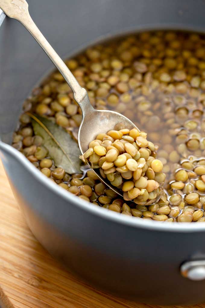 Spooning cooked lentils from a pot