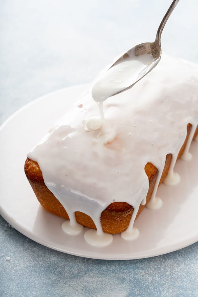 Lemon glaze getting poured over loaf cake.