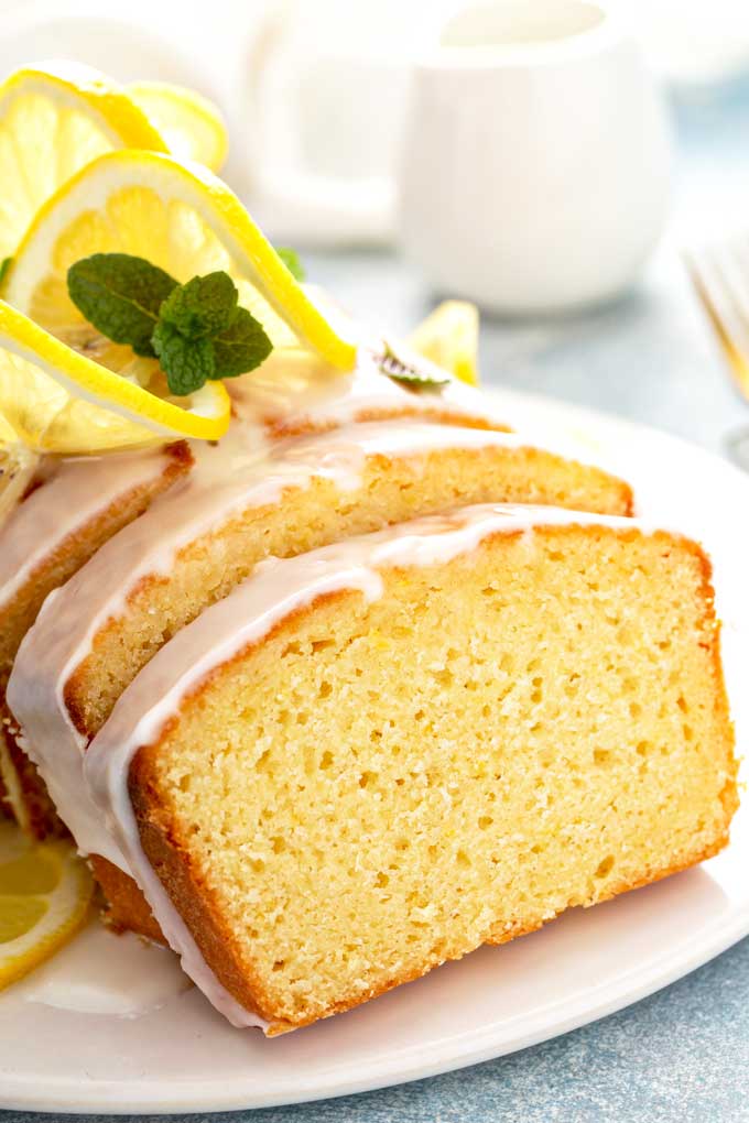 Close up view of a slice of lemon loaf on a white plate.