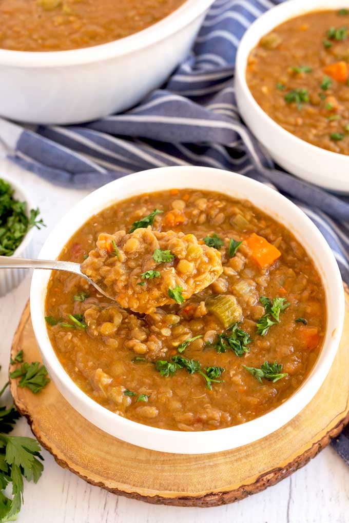 Spoon lifting soup from a white bowl