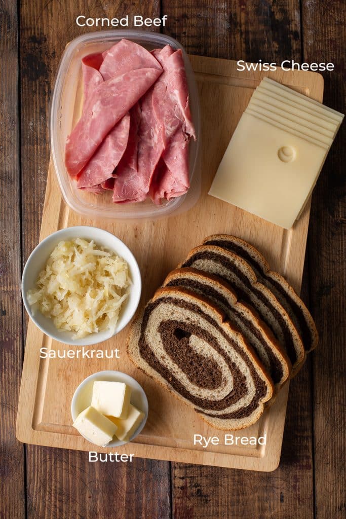 Ingredients to make a Reuben on a wooden board.