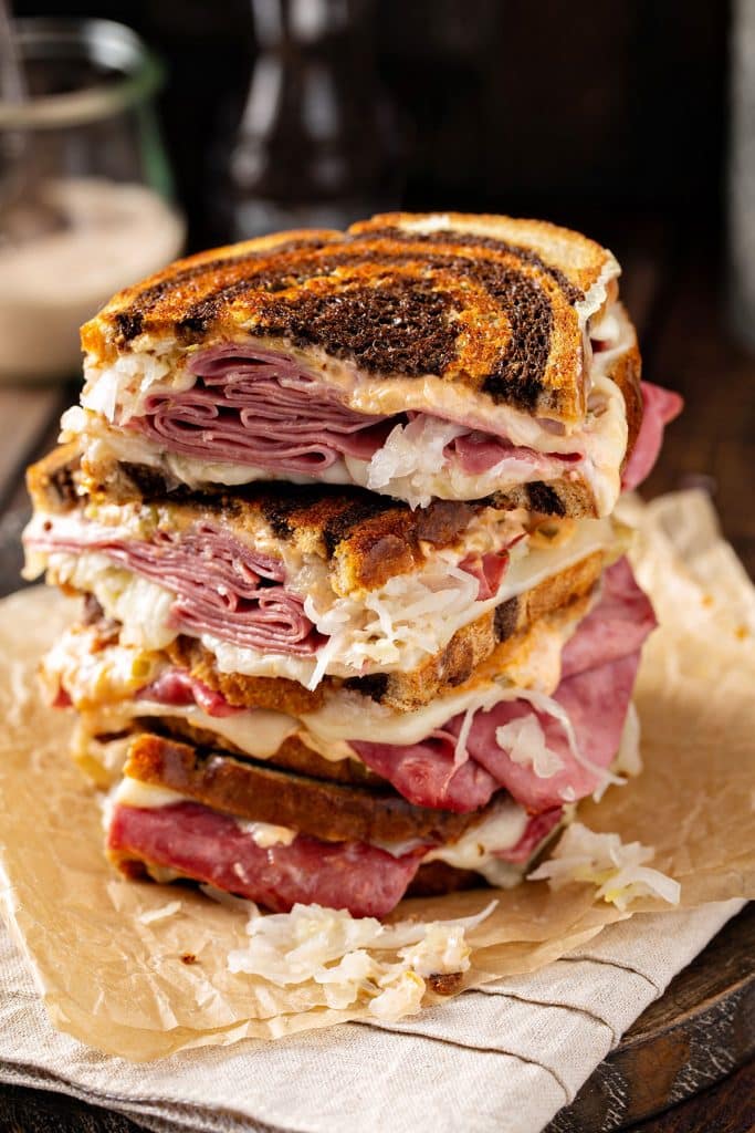 Corned beef sandwiches cut in half and stack on top of parchment paper