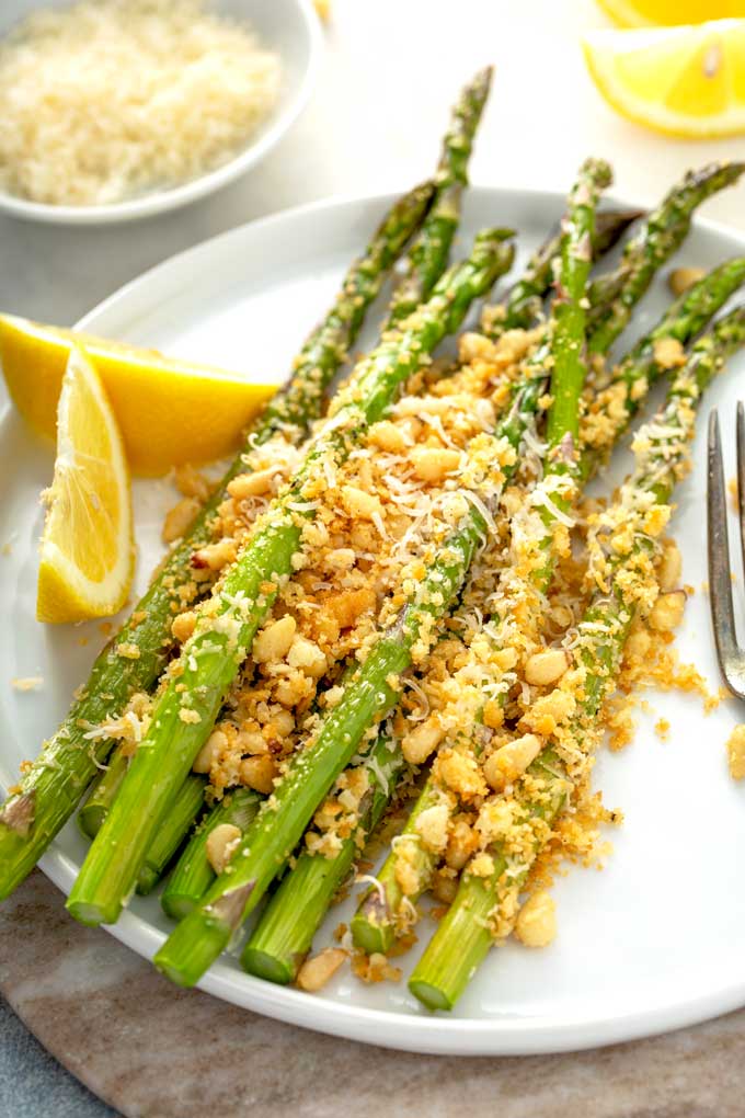 Roasted asparagus with crispy topping on a white plate