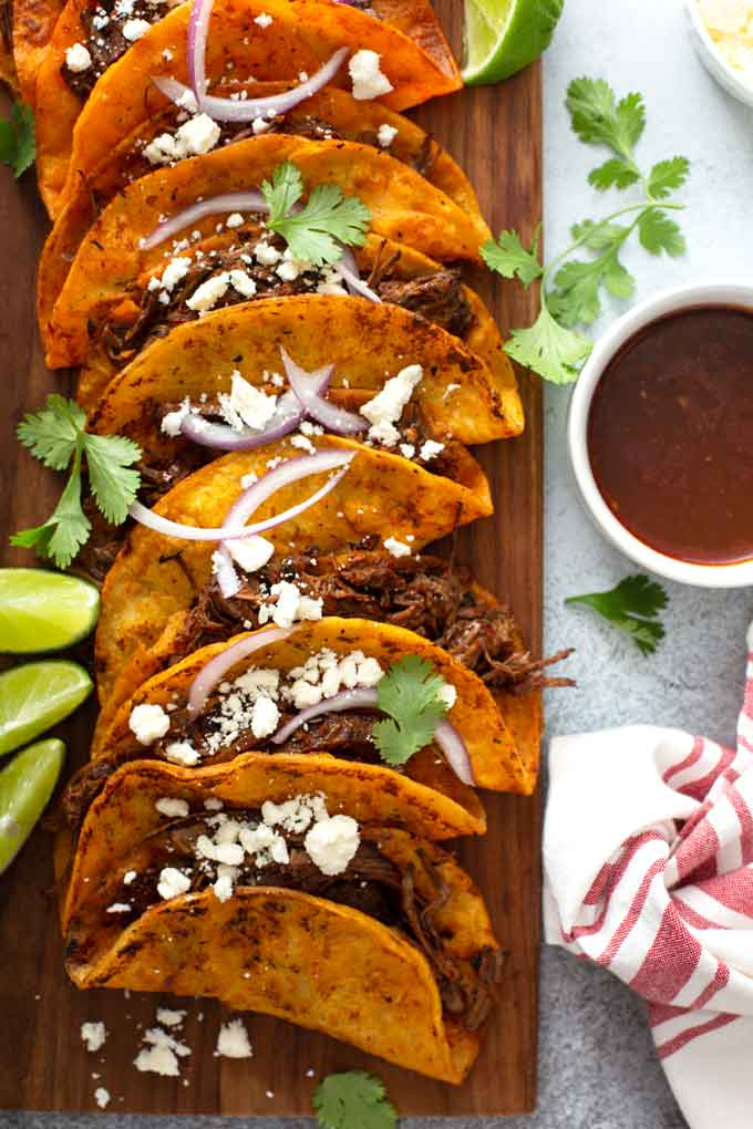 Several birria tacos on a wooden board