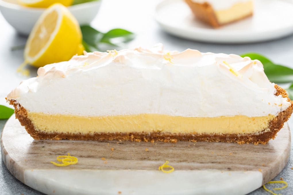 Side view of a lemon pie cut in half showing the creamy center and the fluffy meringue