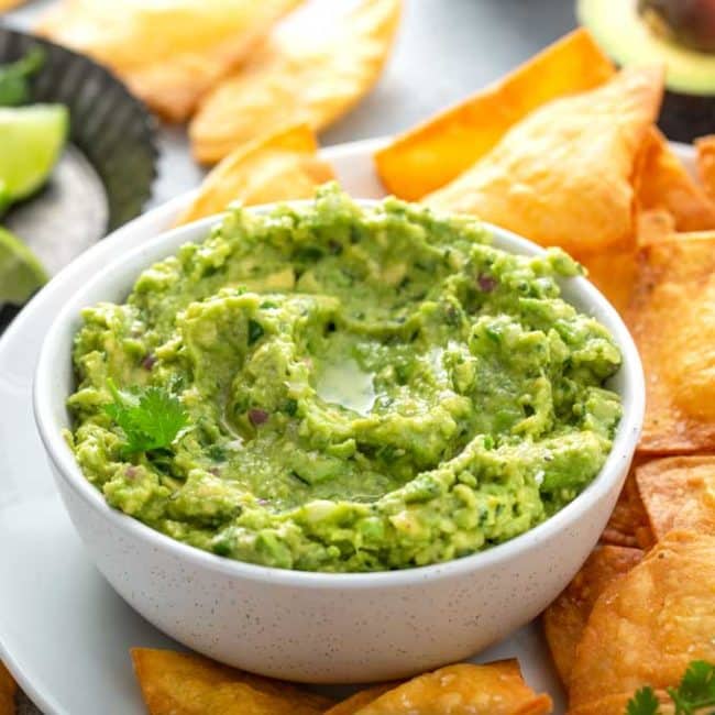 Bowl filled with guacamole surrounded with chips