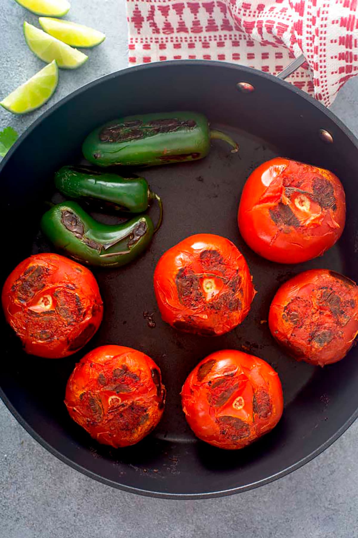 Tomatoes and jalapeños getting charred in a skillet