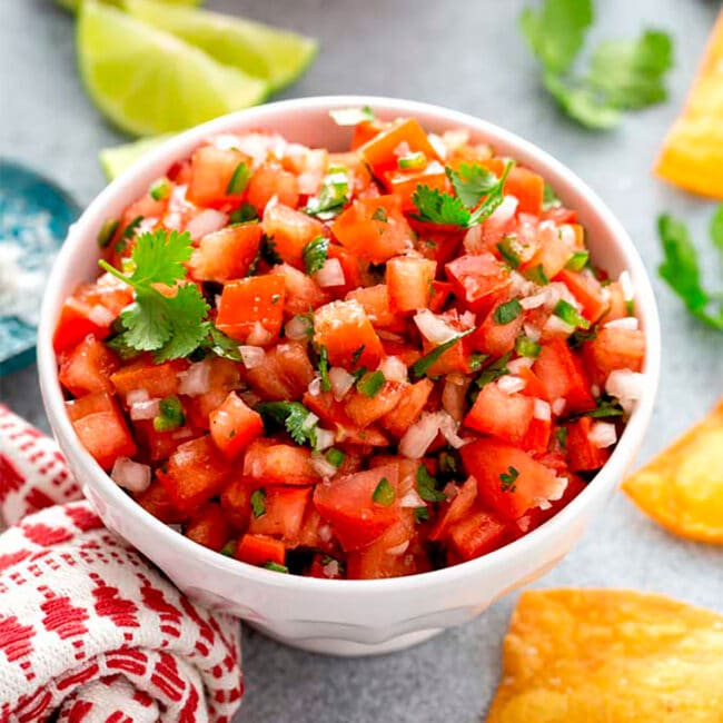 Bowl of pico de gallo with chips and lime
