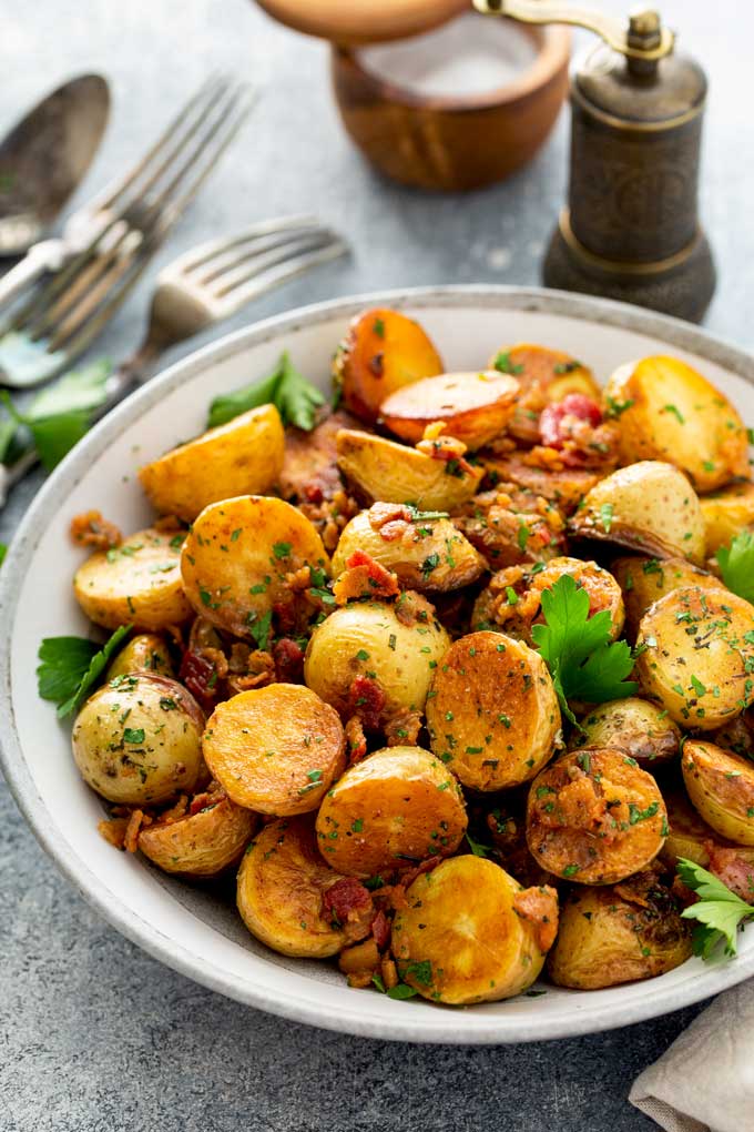 A serving bowl filled with golden sautéed  potatoes