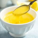Creamy Hollandaise sauce spooned from a white bowl
