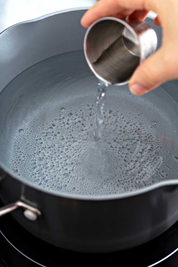 Adding vinegar to a pot of simmering water
