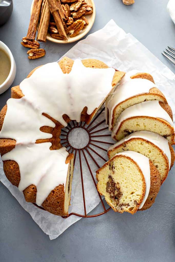 Partially sliced glazed bundt cake with a ribbon of brown sugar, pecans and cinnamon through the middle.