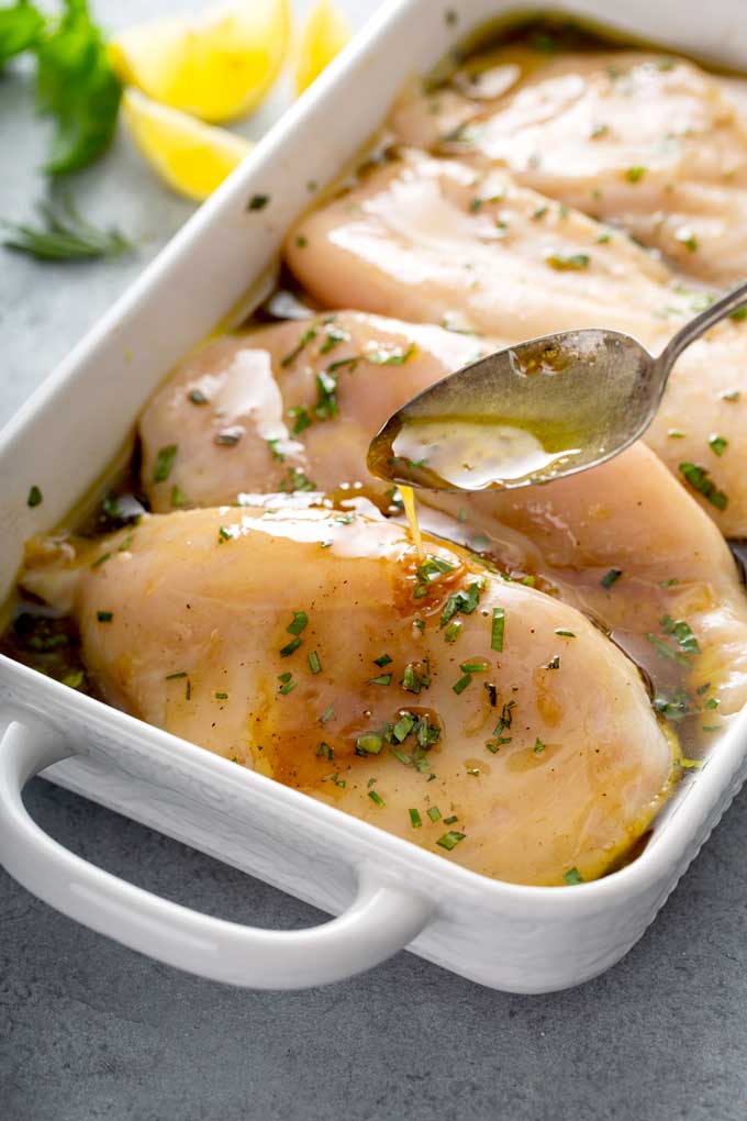 Raw chicken breast in a shallow pan marinating on a balsamic and herb marinade
